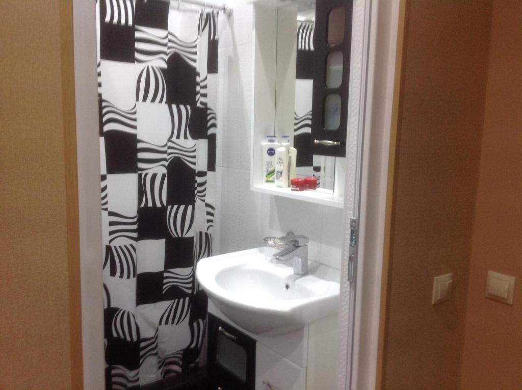 a bathroom with a sink and a black and white shower curtain at Comfortable Apartment near the Sea in K'obulet'i