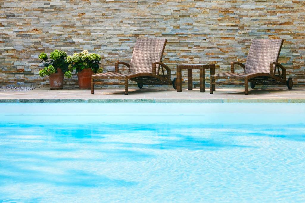 two chairs and a table next to a swimming pool at Kurhotel Markushof in Bad Bellingen