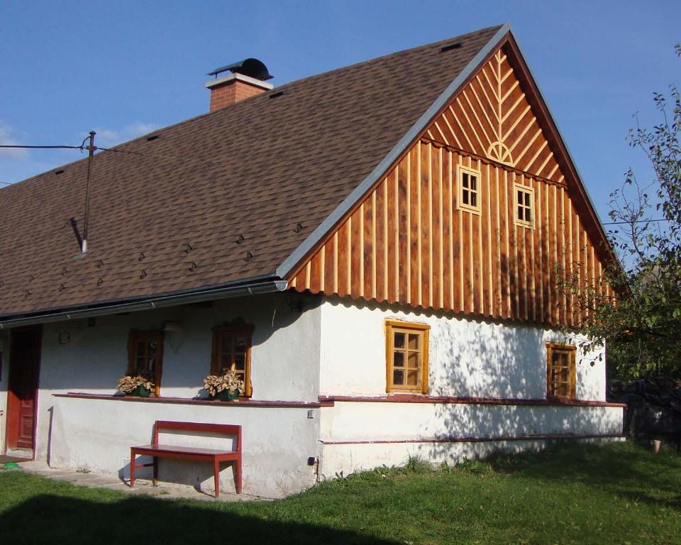 Casa blanca con techo de madera y banco rojo en Chalupa v Pokrkonoší, en Rtyně v Podkrkonoší