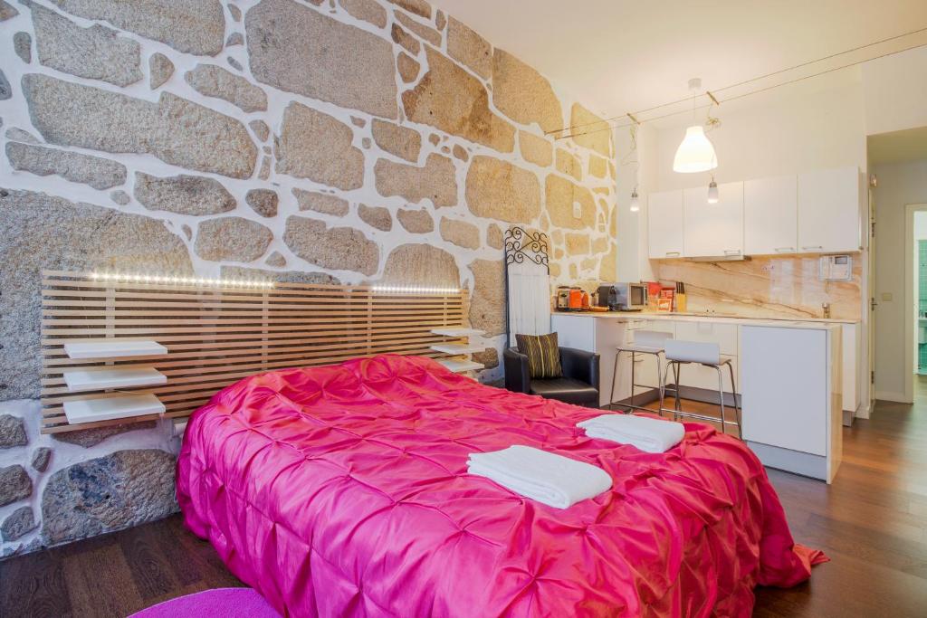 una camera con letto rosa e parete in pietra di OHH - Ganesha studio- Oporto Center a Porto