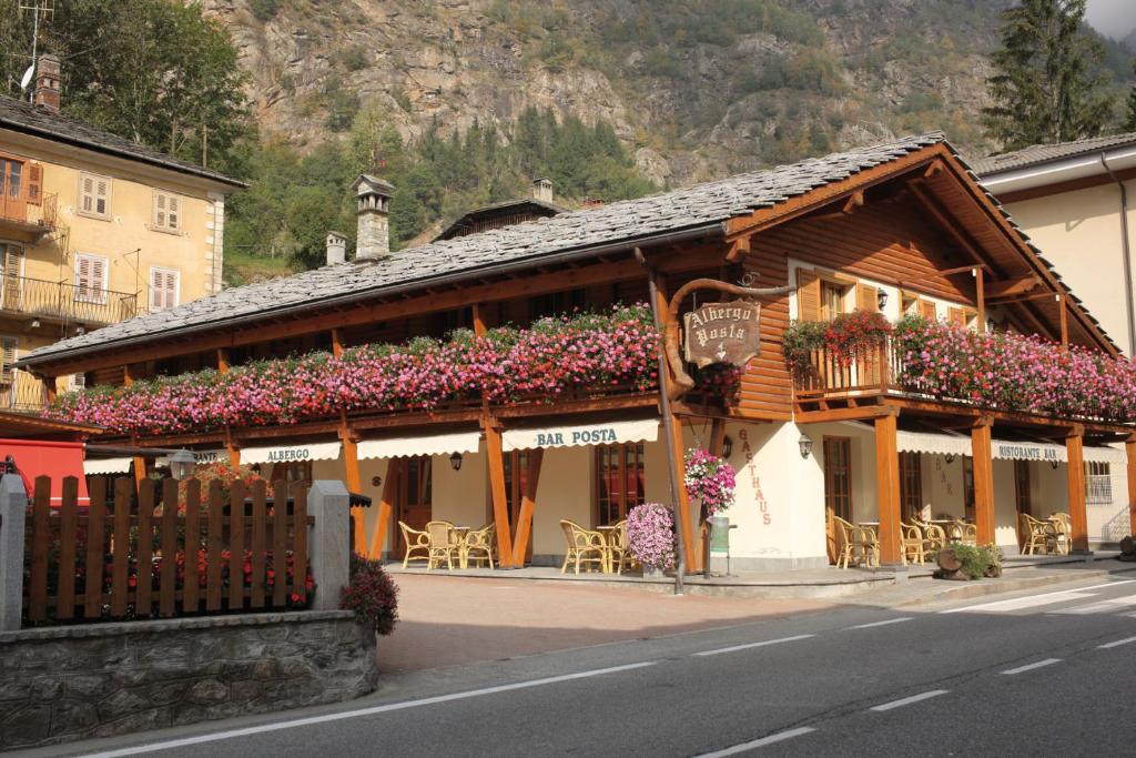 un bâtiment avec des fleurs sur le côté d'une rue dans l'établissement Hotel Posta, à Issime