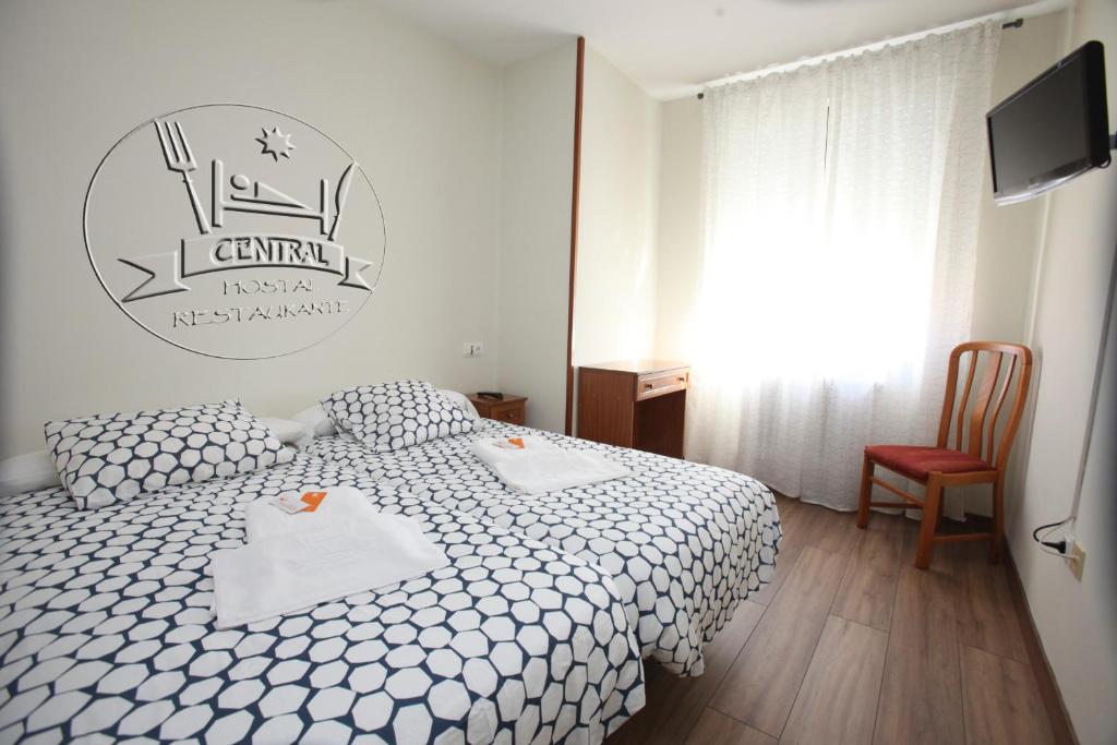 1 dormitorio con 1 cama blanca y TV en Hostal Restaurante Central en La Virgen del Camino