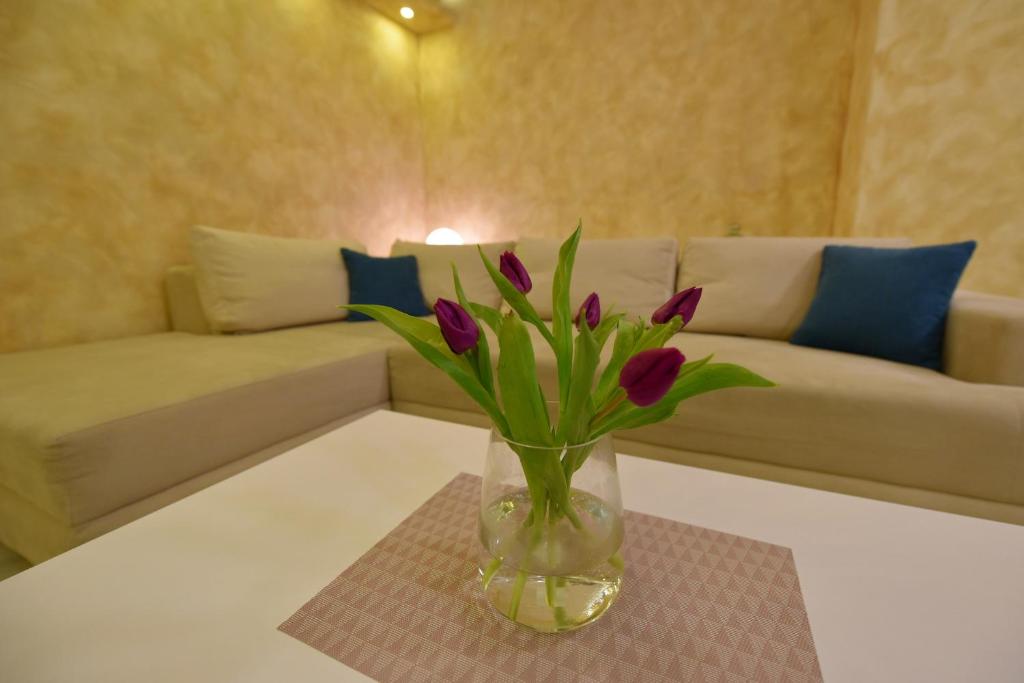um vaso com flores roxas numa mesa numa sala de estar em Apartman Centar Bg em Belgrado
