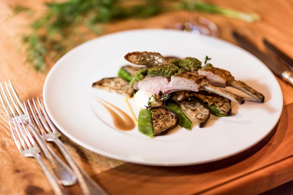 a white plate of food on a wooden table at Hotel Genziana in Selva di Val Gardena