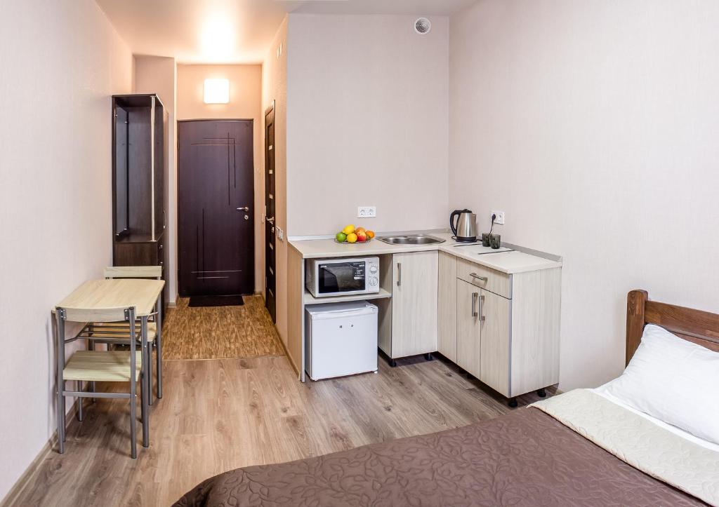 Apart Hotel Smart Studio في خاركوف: غرفة بسرير ومطبخ وطاولة