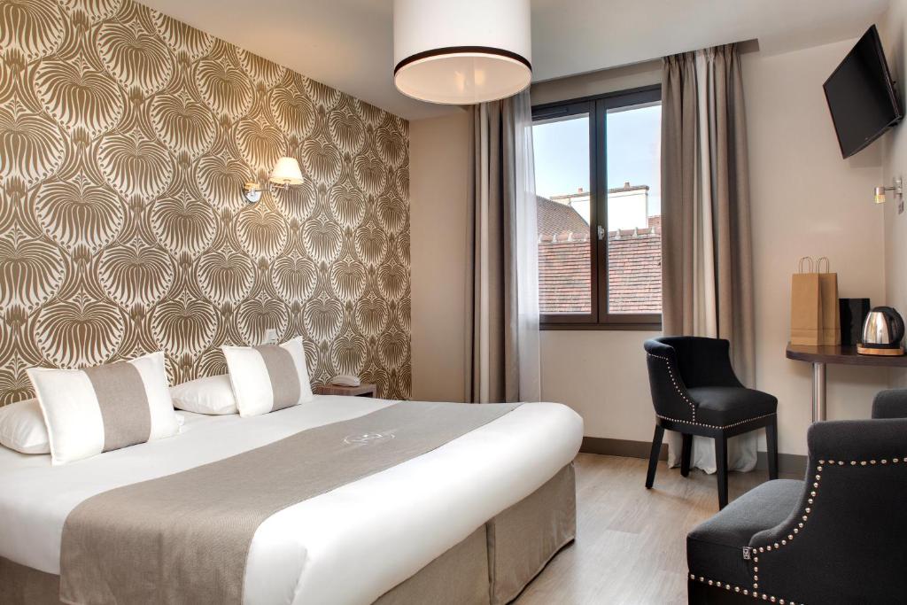 a hotel room with a bed and a chair at Hôtel des Ducs in Dijon