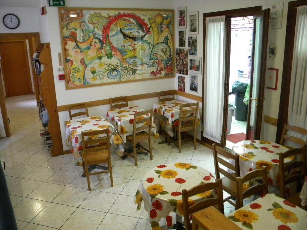 a restaurant with tables and chairs and a painting on the wall at Hotel Adua in Venice