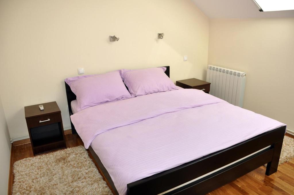 1 dormitorio con 1 cama con sábanas moradas y 2 mesitas de noche en Apartments Soleado, en Pančevo
