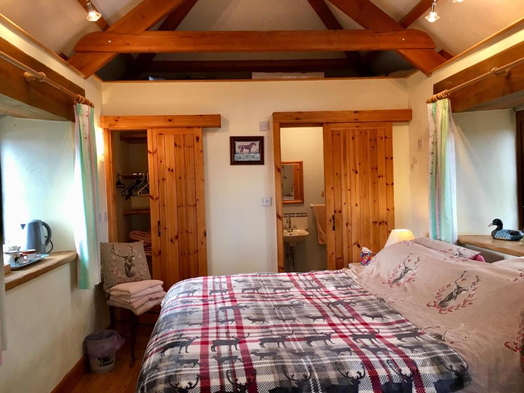 a bedroom with a bed and wooden ceilings at The Stable in Saint Clether