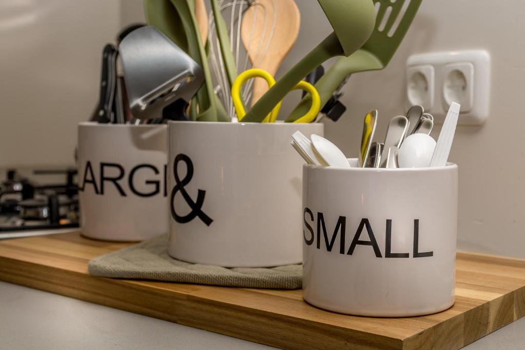 three white cups on a wooden shelf with utensils at Zoet Valkenburg in Valkenburg