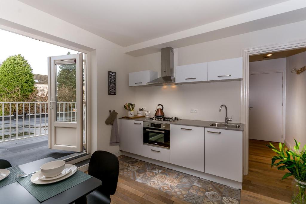 a kitchen with white cabinets and a table and a dining room at Zoet Valkenburg in Valkenburg