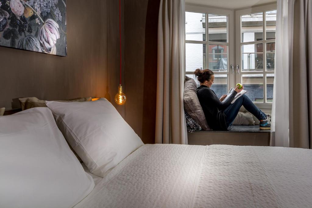 a woman sitting on a window sill reading a book at Zoet Valkenburg in Valkenburg