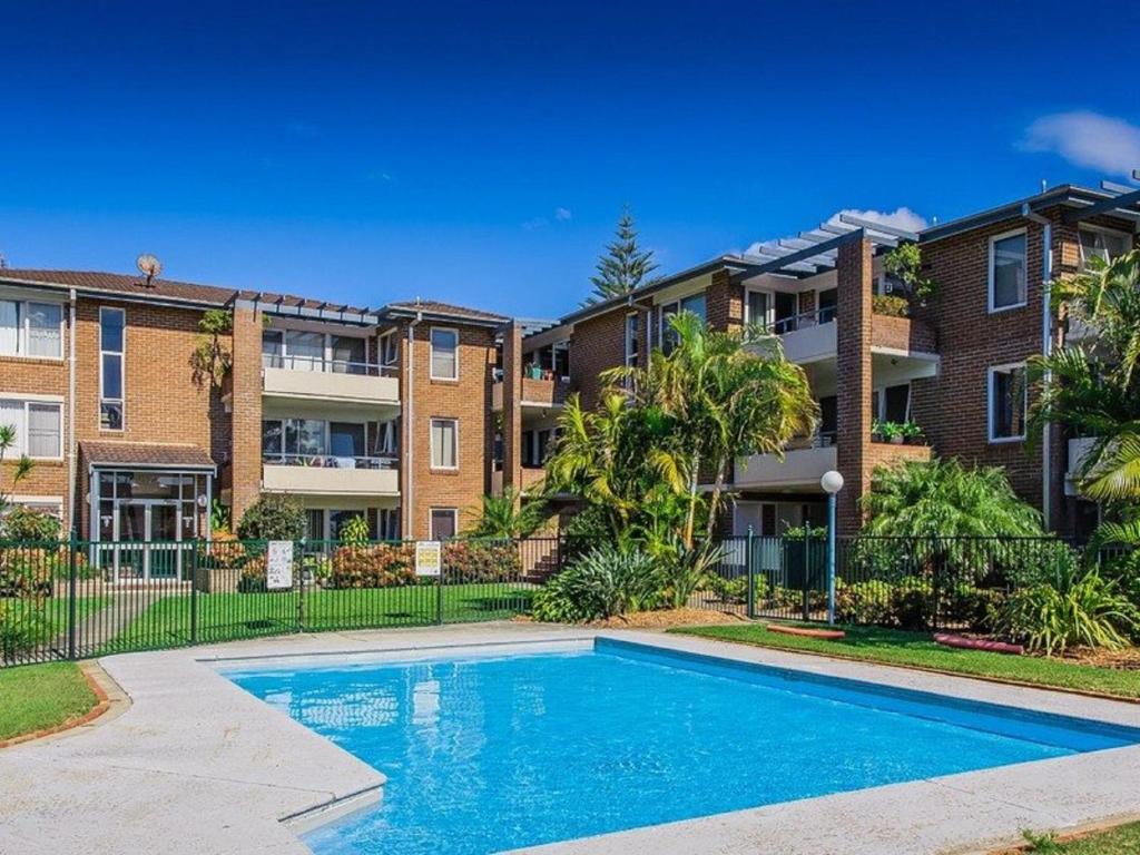 an apartment complex with a swimming pool in front of a building at Bay Park Gardens 30 1 Warlters Street in Port Macquarie