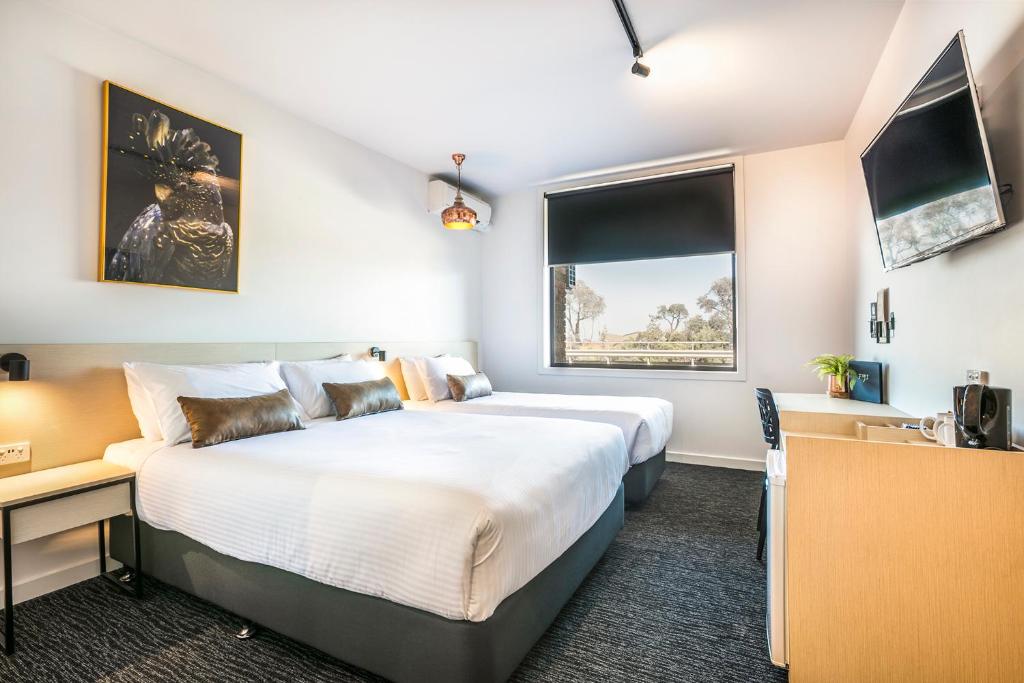 um quarto de hotel com uma cama grande e uma janela em Nightcap at The Cheeky Squire em Frankston