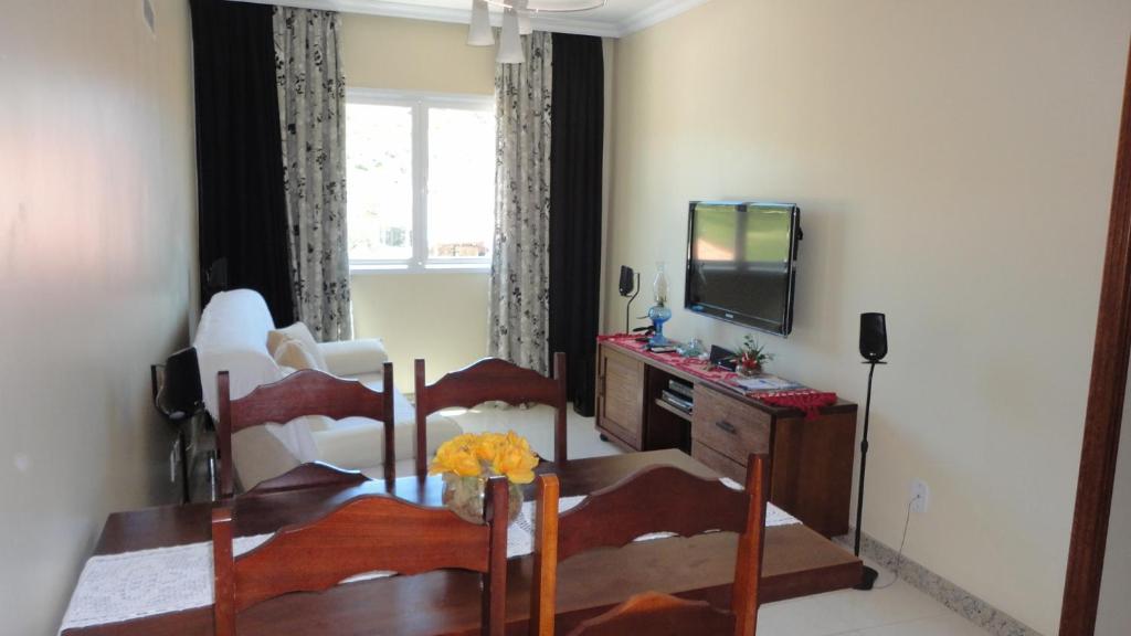 a living room with a dining table and a television at Prainha Lindo Apto com 02 quartos e 02 vagas de garagem in Arraial do Cabo