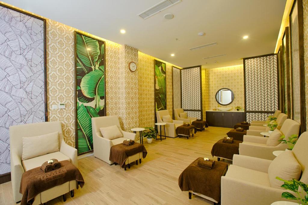 A bright waiting lounge is arranged with cream armchairs, ottomans, plants, and decorative screens.