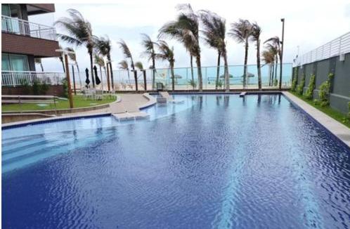 a large swimming pool with palm trees in a building at Beach Way - Apartamento no Porto das Dunas in Fortaleza