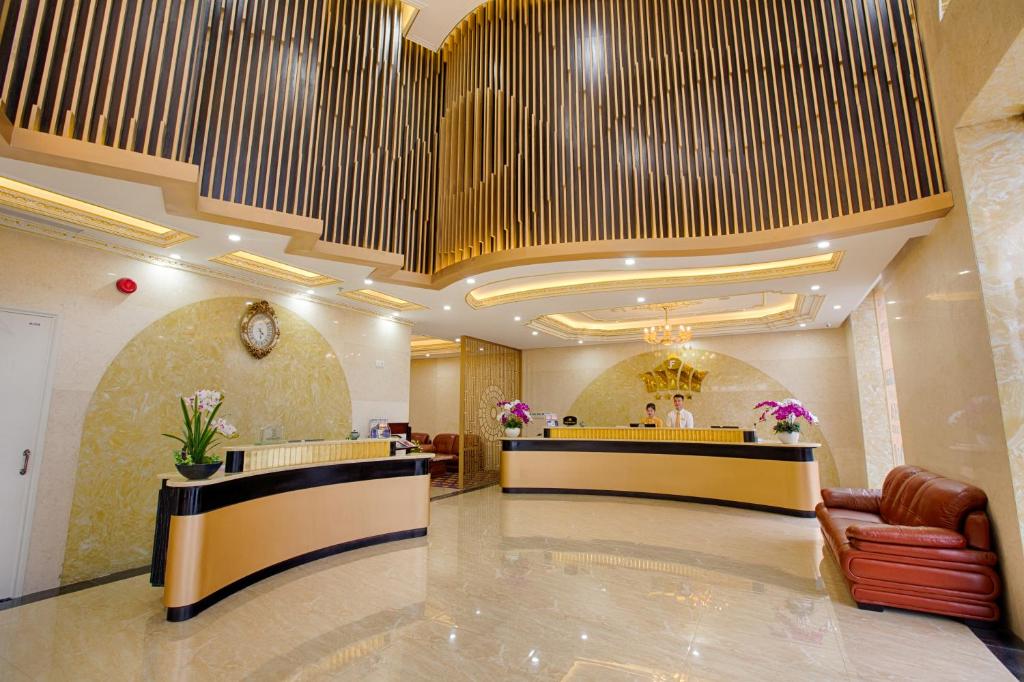 A polished hotel reception lobby with two curved desks and a small seating area.