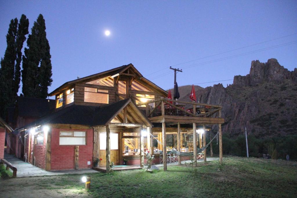 une maison en rondins avec la lune dans le ciel dans l'établissement Montaña Negra, à Aluminé