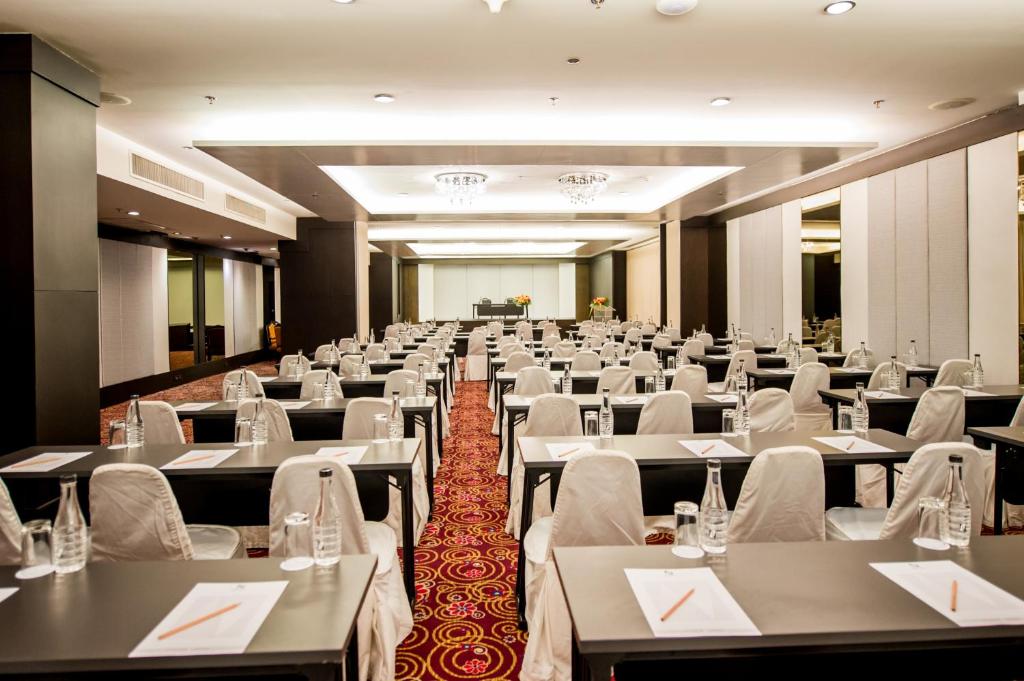 A large formal dining hall fully laid out with white-covered chairs and place settings.