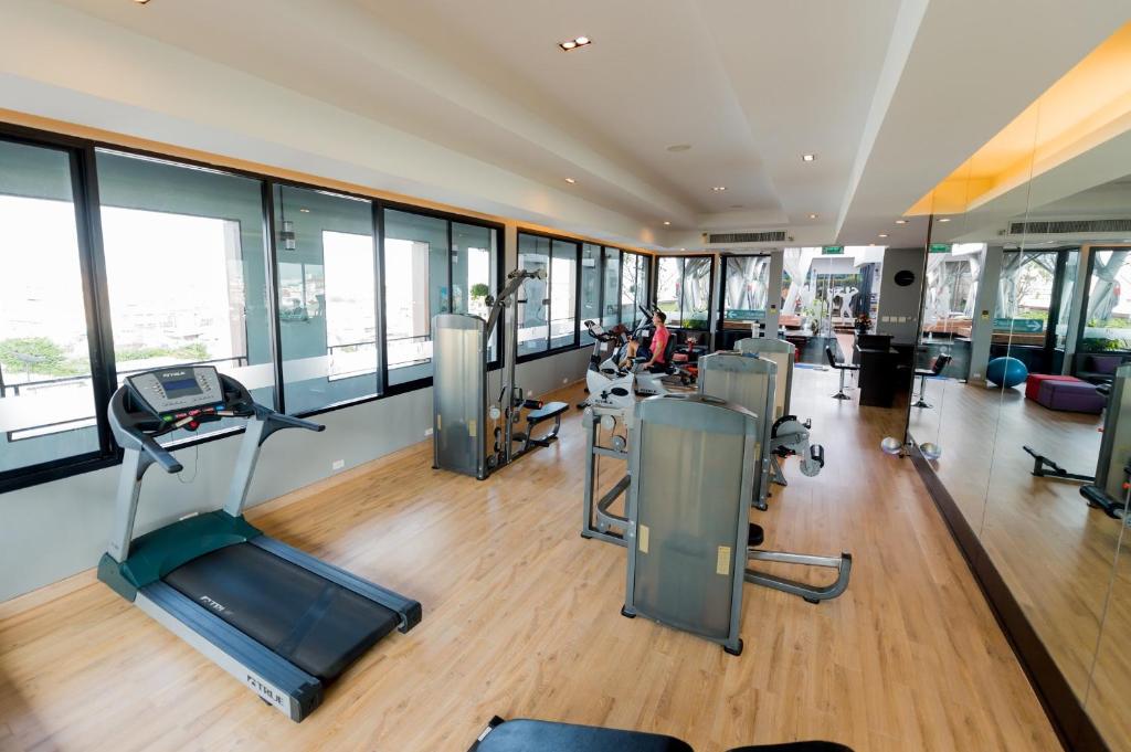 A bright, glass-fronted fitness room with cardio and weight machines.