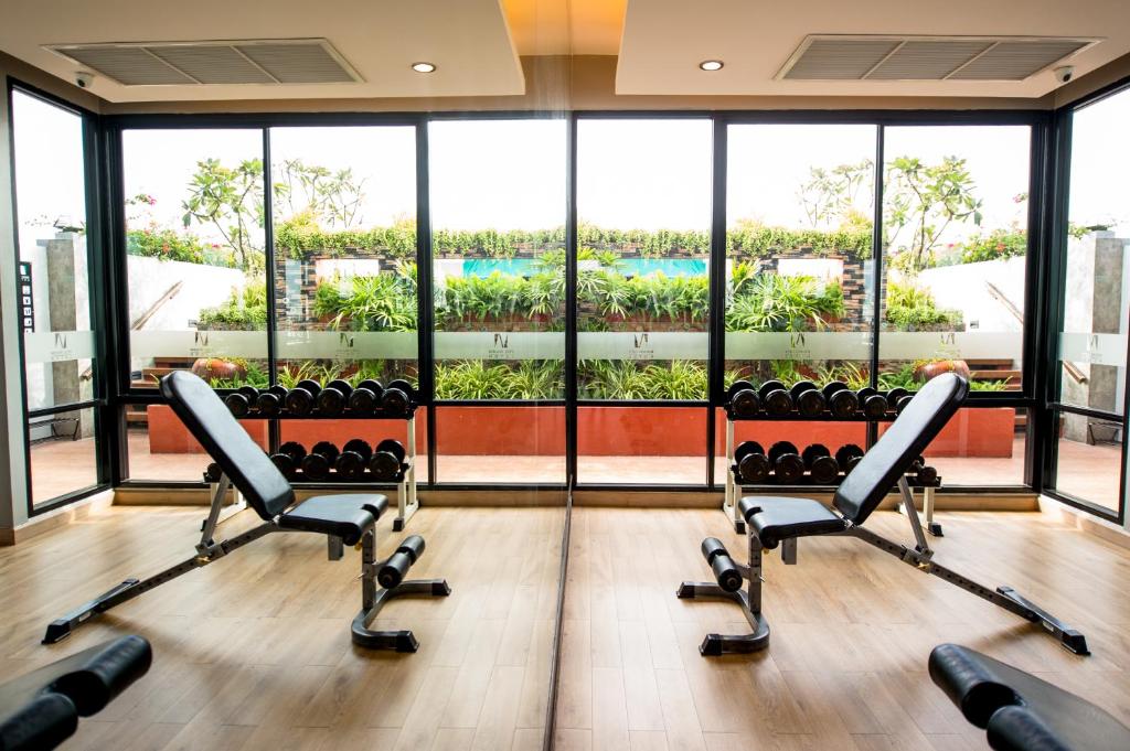 A compact, naturally lit gym with adjustable benches and dumbbell racks facing greenery.