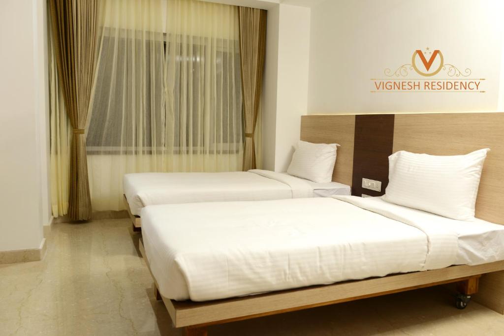 2 letti in camera d'albergo con lenzuola bianche di Vignesh Residency a Tiruchchirāppalli
