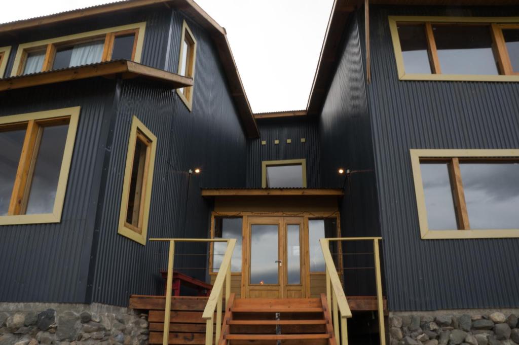 a black house with a front door and stairs at Hostería La Soberana in El Calafate