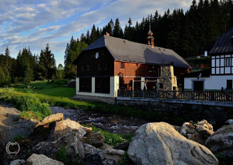 カシュペルスケー・ホリにあるPenzion Pupíkの川の横の茶色と白の大きな建物