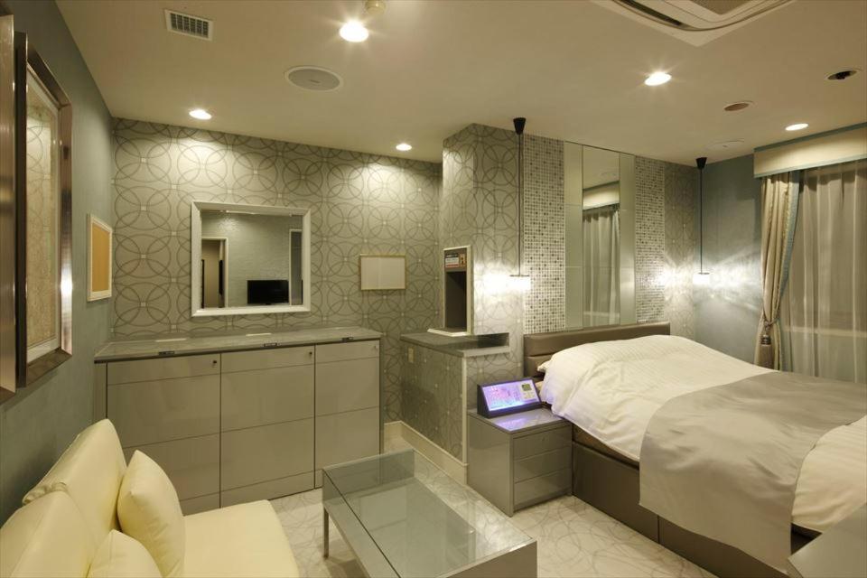 Hotel Waltz Okazaki (Adult Only) في أوكازاكي: غرفة نوم مع سرير وجهاز كمبيوتر محمول على طاولة