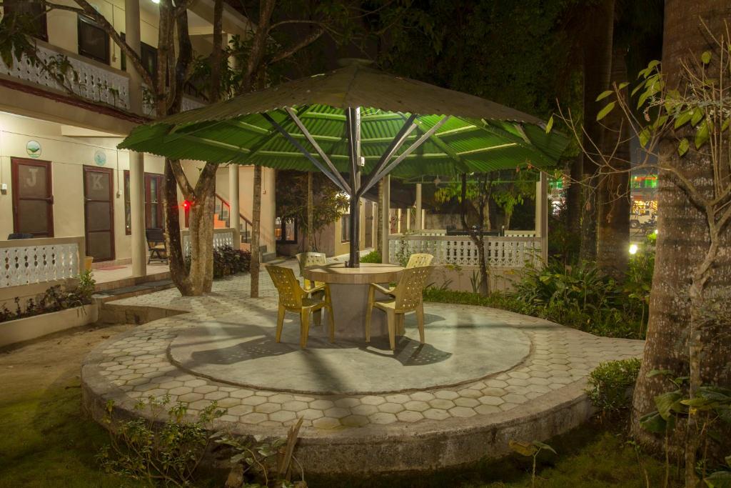 a table and chairs under a green umbrella at Sauraha Resort in Sauraha