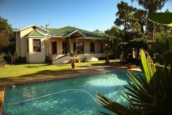 a house with a swimming pool in front of a house at Peppertree House BnB and Self-catering in Fort Beaufort