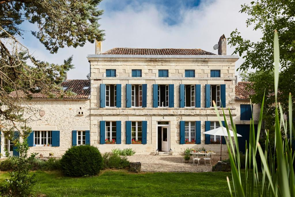 una casa vieja con persianas azules y un patio en Manoir Laurette, en Saint-Martin-Petit