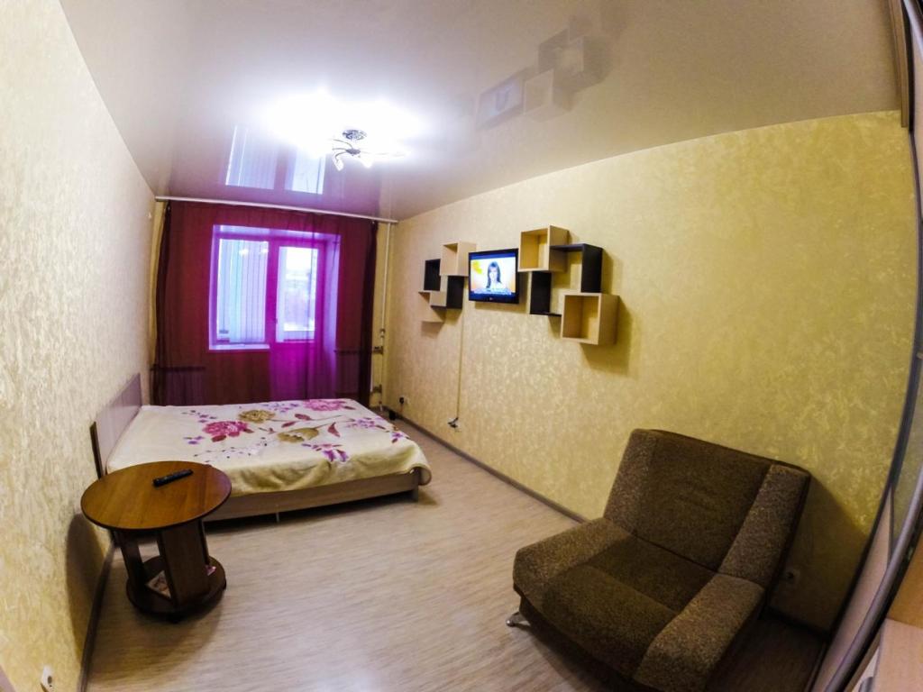 ペルミにあるApartments on Lenina 72Bのベッドルーム1室(ベッド1台、椅子、テーブル付)