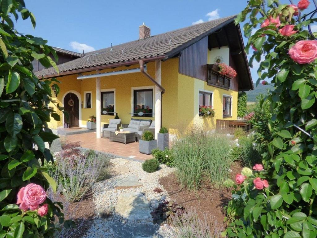 ein gelbes Haus mit einer Terrasse und Rosen in der Unterkunft Landhaus Simon in Gleißenberg