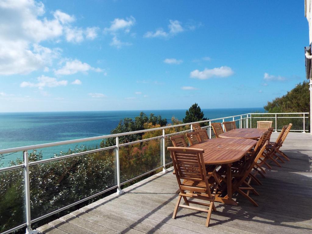 un tavolo in legno con sedie su un balcone con vista sull'oceano di Villa le Rayon Vert a Saint-Pierre-en-Port