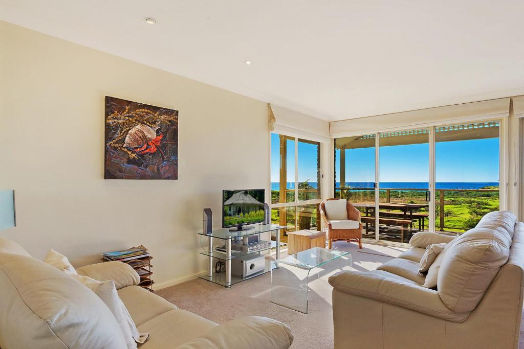 a living room with two couches and a tv at Beach Breakers Apartment Stunning Views in Kianga