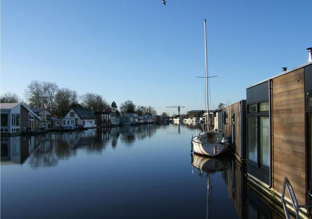 a boat is docked in a canal next to houses at watervilla-albertje in Amsterdam