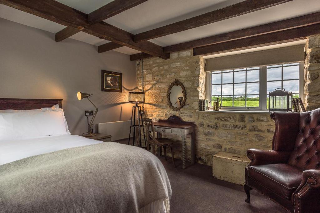 a bedroom with a bed and a chair and a window at Widbrook Grange in Bradford on Avon
