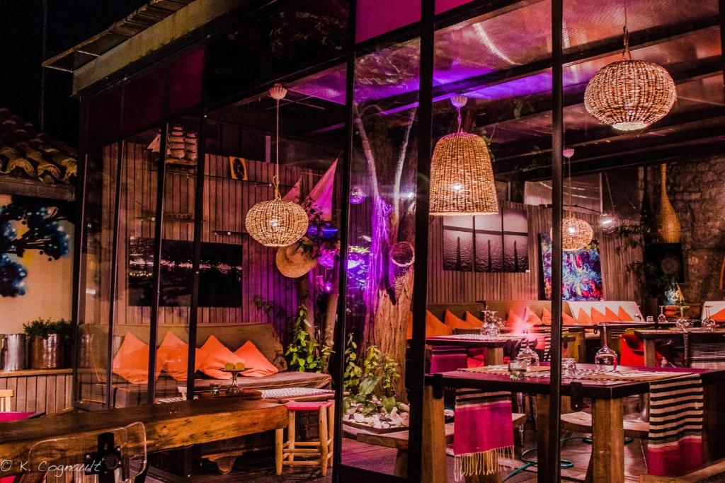 un restaurante con mesas, sillas e iluminación púrpura en La Stregheria, en Plage de La Franqui