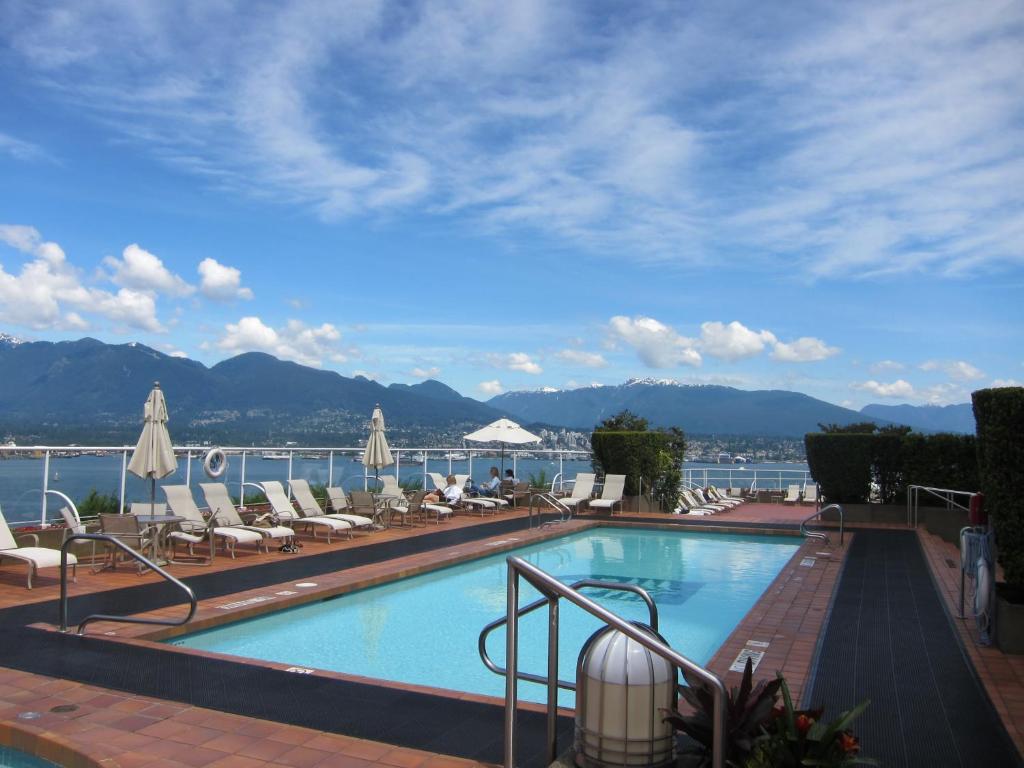 a swimming pool with chairs and a view of the water at Pan Pacific Vancouver in Vancouver