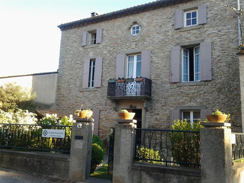 una casa de piedra con una puerta y una valla en La Belle Minervoise, en Saint-Frichoux