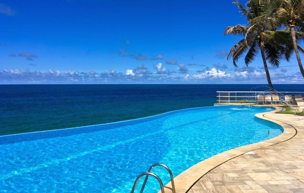 a swimming pool with the ocean in the background at Mercure Salvador Rio Vermelho in Salvador