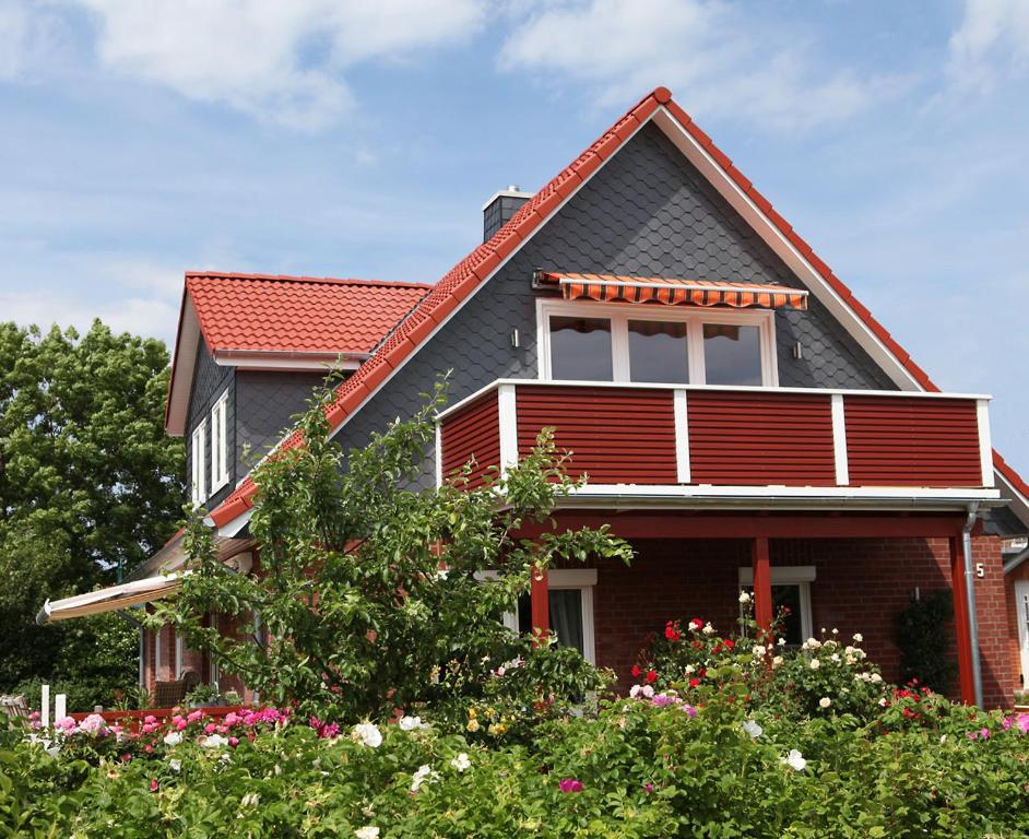 una casa con techo rojo y algunas flores en Kranichnest en Hohwacht