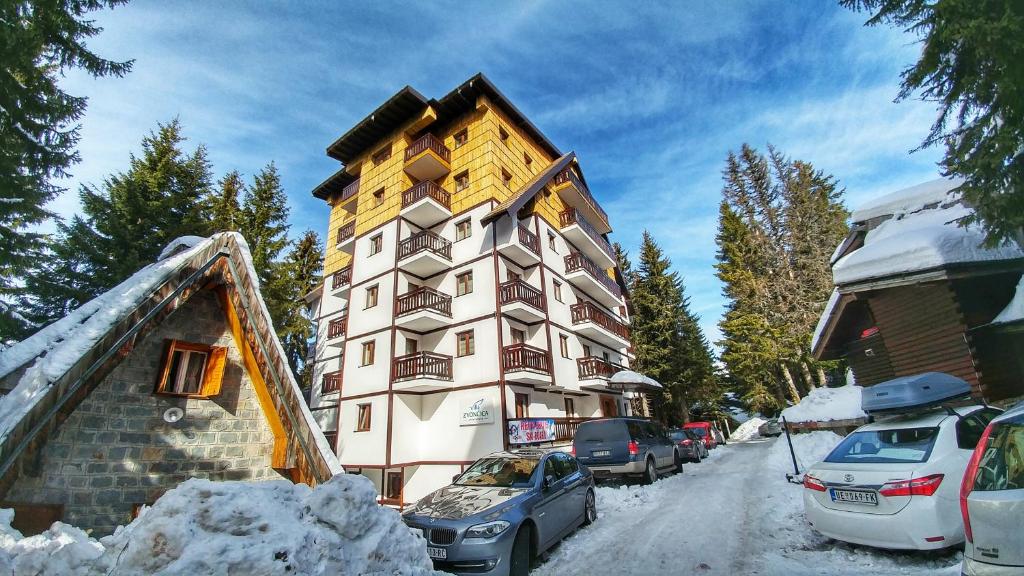 a building in the snow with cars parked next to it at Apartments Zed Vila Zvoncica in Kopaonik