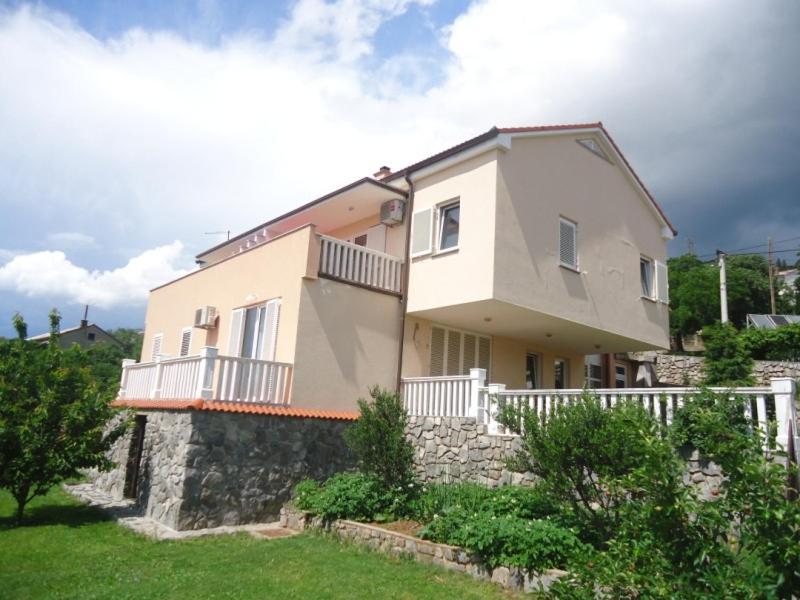 a large white house with a stone wall at Apartments Ante in Senj