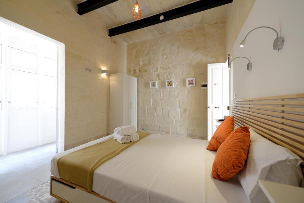 a bedroom with a large bed with orange pillows at Lovely House Private Rooms by Vallettastay in Valletta