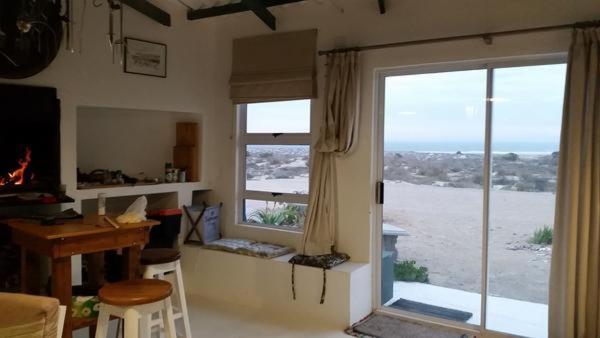 Zimmer mit einem Schreibtisch und einem Fenster mit Blick auf den Strand. in der Unterkunft Beach Cottage Kleinzee in Kleinsee