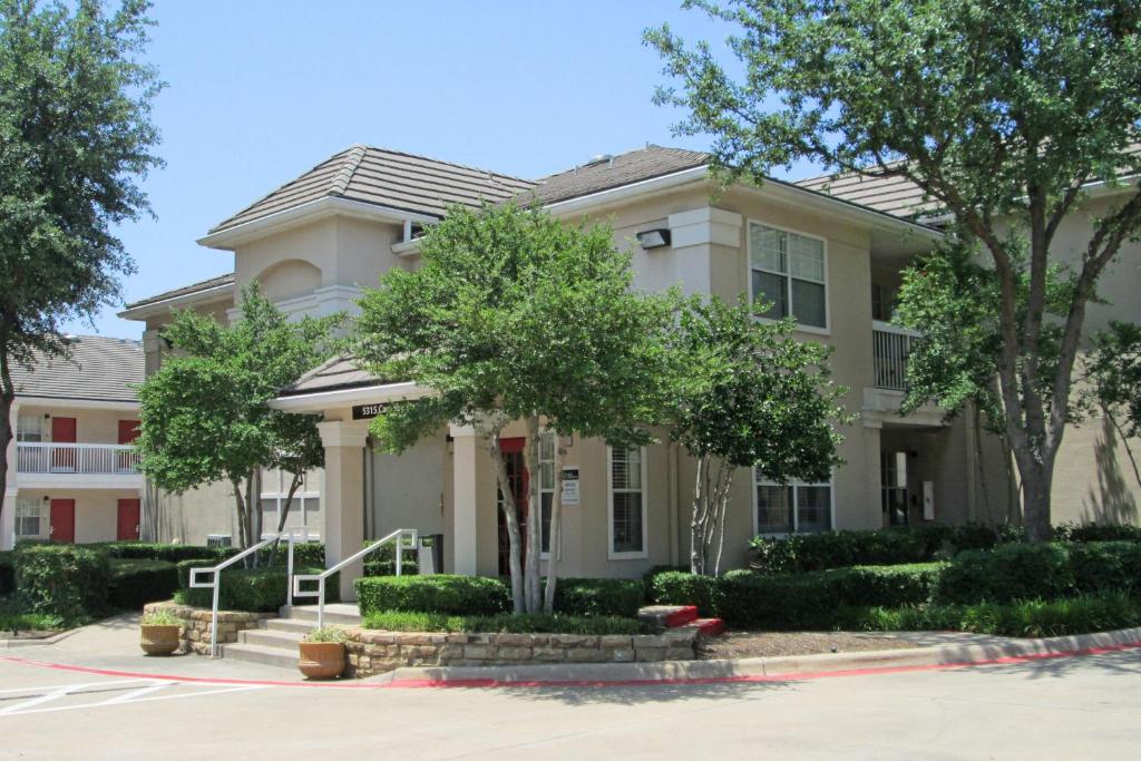 a white house with trees in front of it at Extended Stay America Suites - Dallas - Las Colinas - Carnaby St in Irving