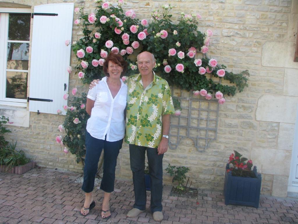 a man and a woman standing in front of a wall of roses at Le Logis d&#39;ANTIGNY in Val-du-Mignon